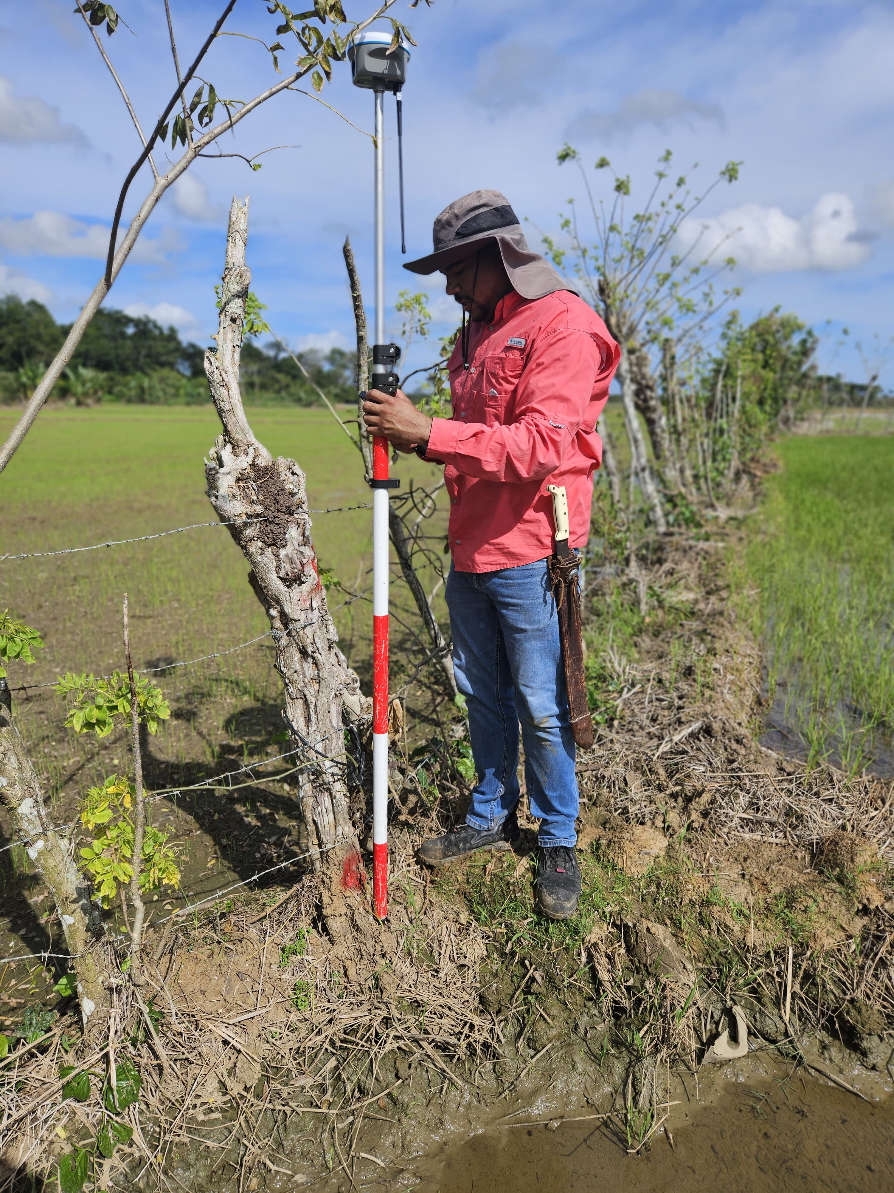 Surveyor using APEKS AP10 RTK GNSS in a muddy agricultural field in the Dominican Republic