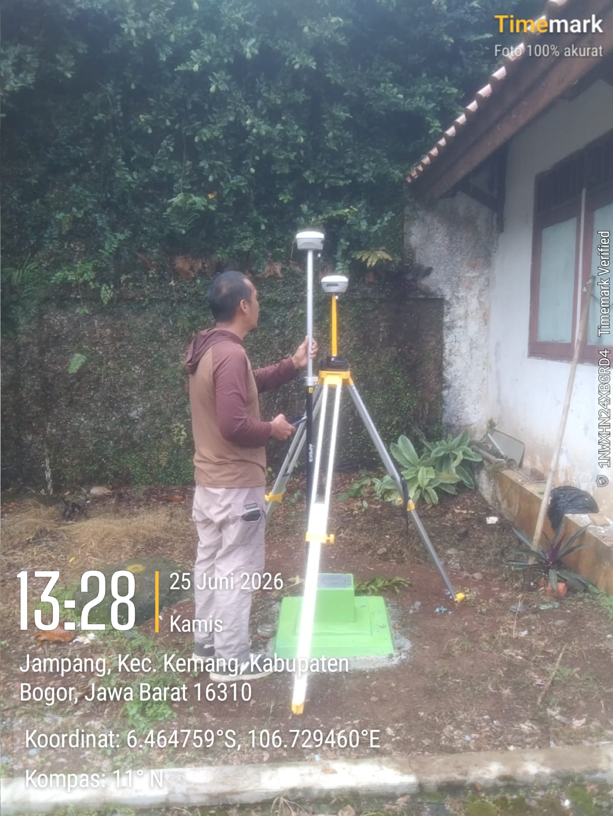 APEKS GNSS base station setup on a tripod over a green geodetic benchmark pillar in Bogor, Indonesia