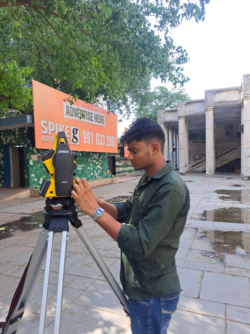 Seorang surveyor profesional mengoperasikan total station optik APEKS AM02 untuk membangun jaringan traverse struktural presisi tinggi di India.
