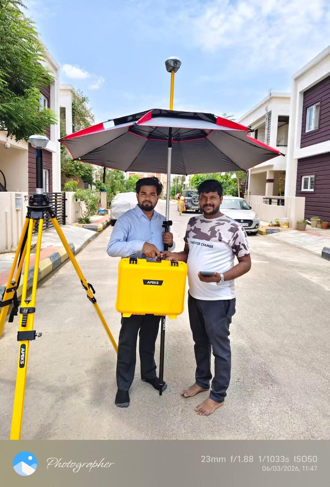 Para surveyor menggunakan payung survei kadaster APEKS dan peralatan RTK untuk pelacakan batas di sebuah pengembangan perumahan di India oleh CStech Survey & Co.