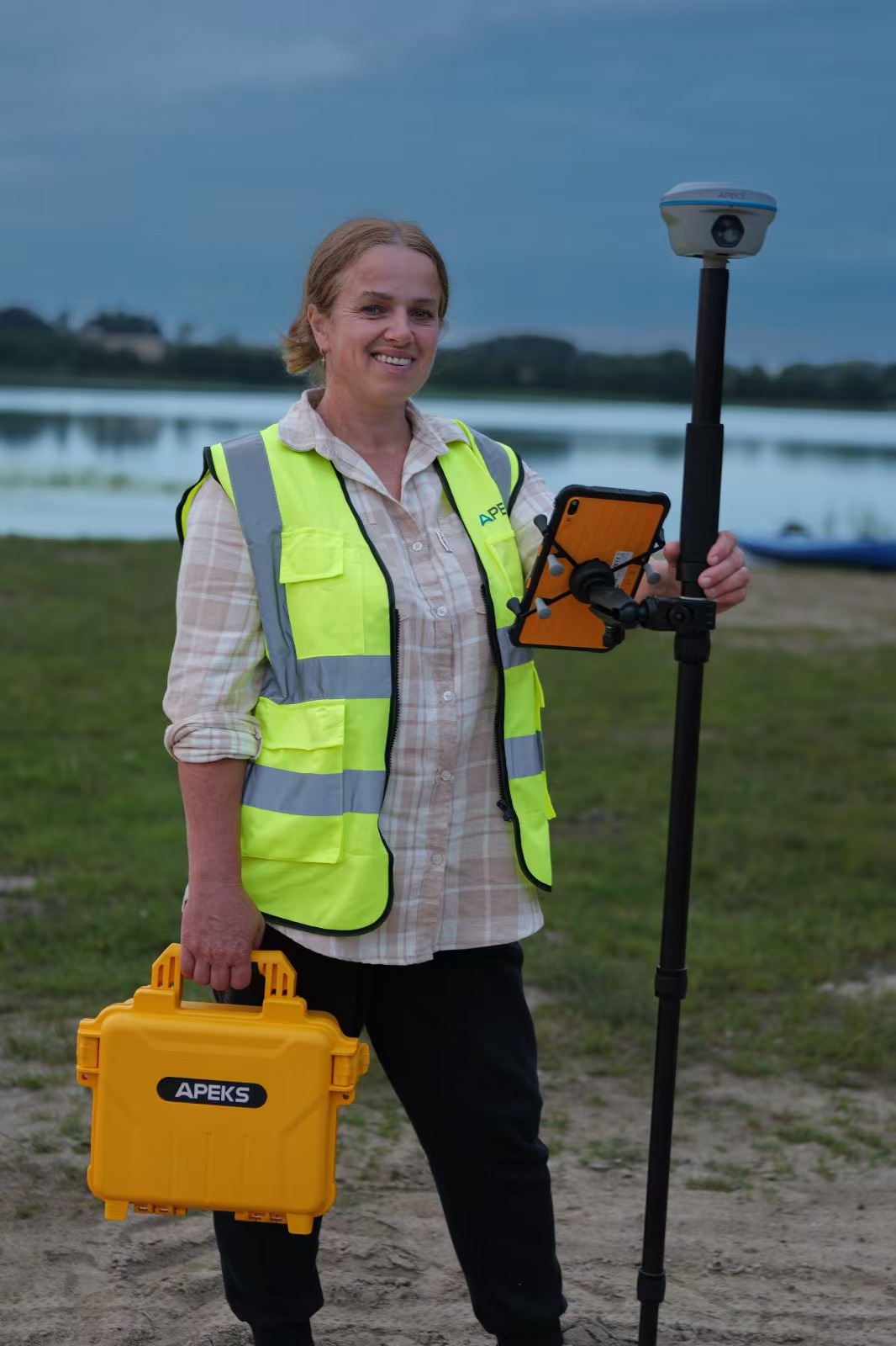 Surveyor holding the signature yellow APEKS hard carry case and rover kit near a lake in Poland
